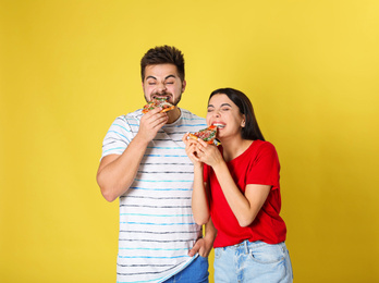 Emotional couple eating pizza on yellow background