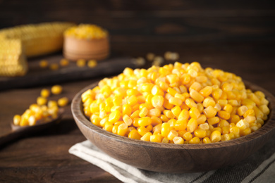 Photo of Delicious canned corn in bowl on wooden table, closeup