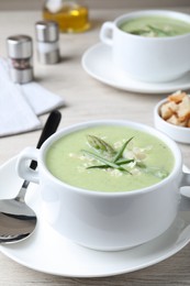 Delicious asparagus soup with green onion served on white wooden table
