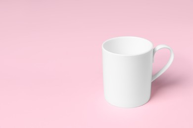 Photo of One white ceramic mug on pink background, space for text