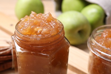 Photo of Delicious apple jam in jars and fresh fruits on wooden table, closeup