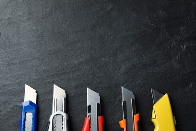 Photo of Different utility knives on black table, flat lay. Space for text