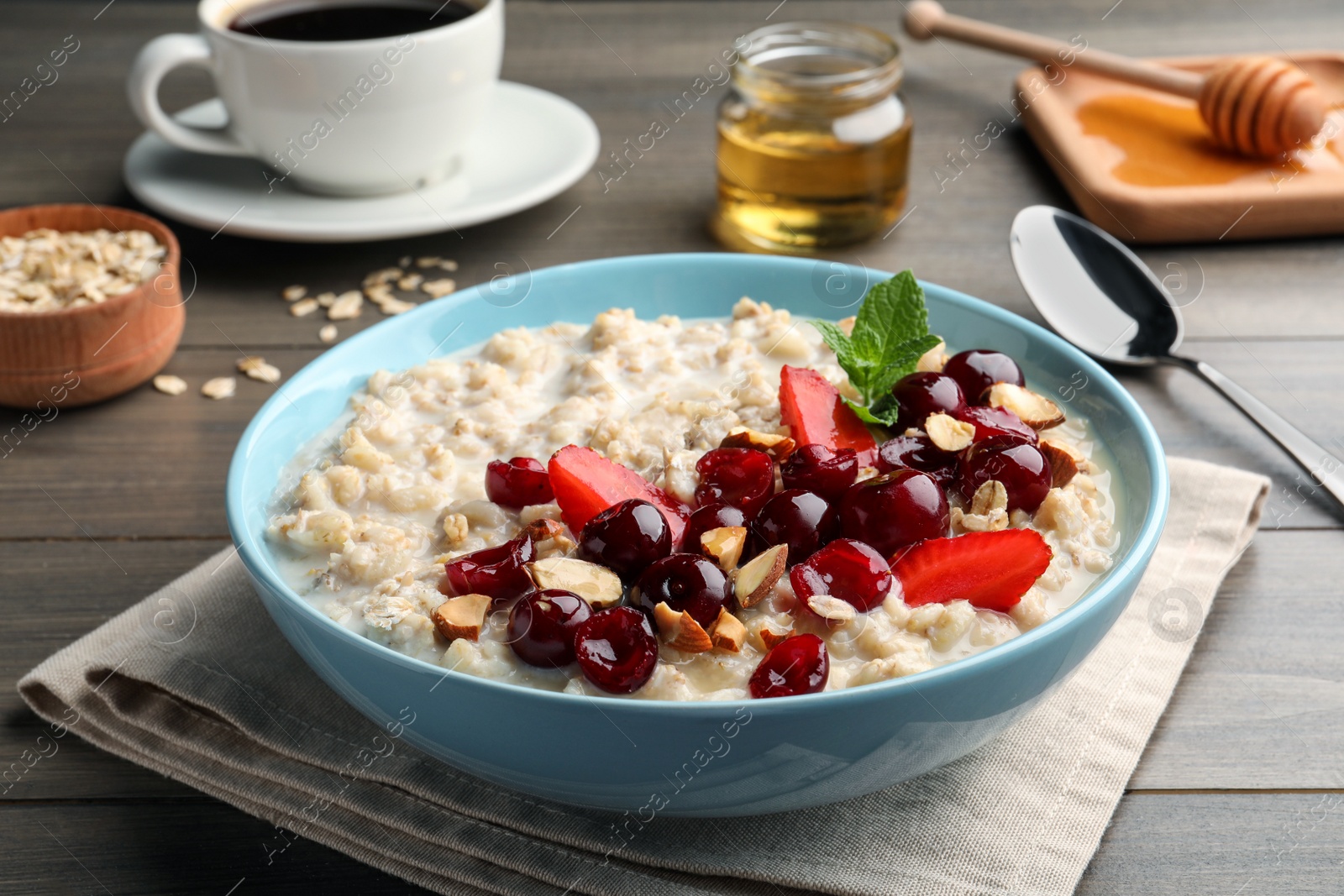 Photo of Bowl of oatmeal porridge served with berries on wooden table