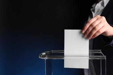 Photo of Woman putting her vote into ballot box on dark blue background, closeup. Space for text