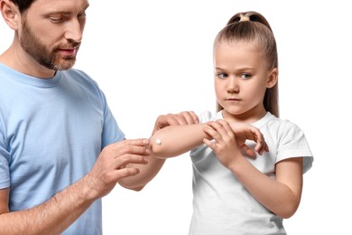 Photo of Father applying ointment onto his daughter's elbow on white background