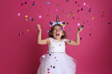 Photo of Adorable little girl and falling confetti on pink background