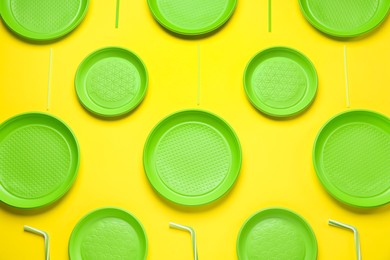 Photo of Plastic dishware on yellow background, flat lay