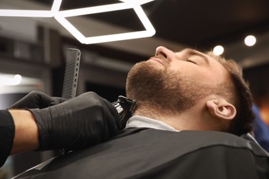 Photo of Professional hairdresser working with client in barbershop