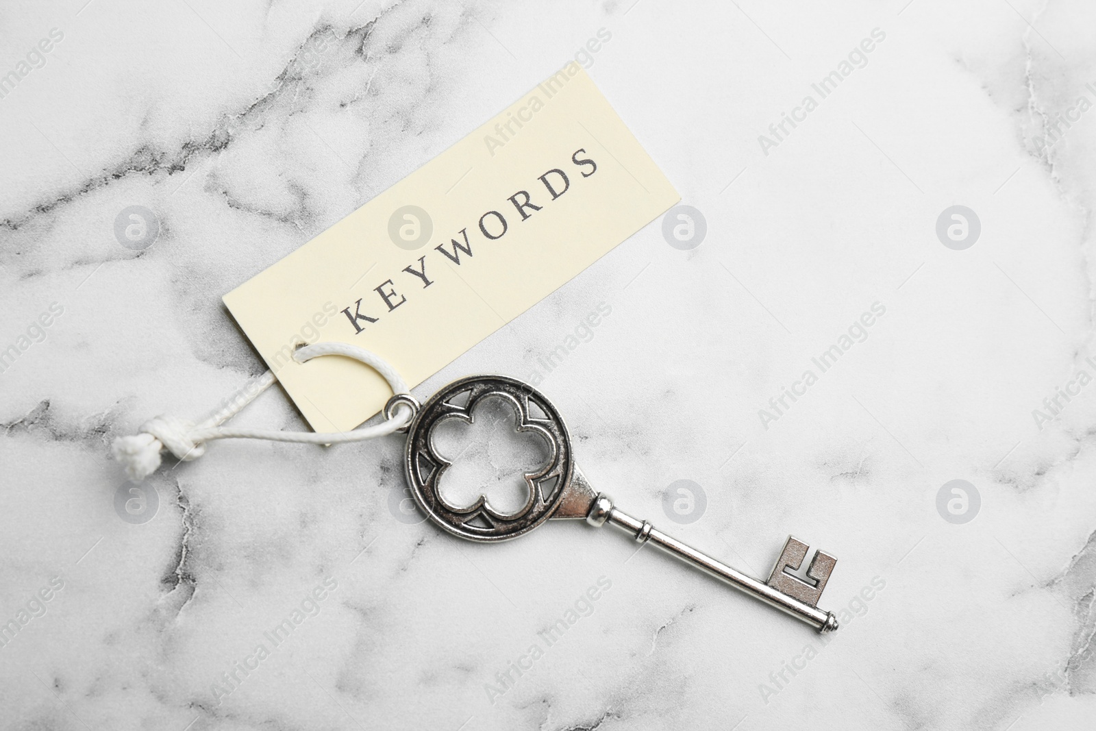 Photo of Vintage key and tag wIth word KEYWORDS on white marble table, top view