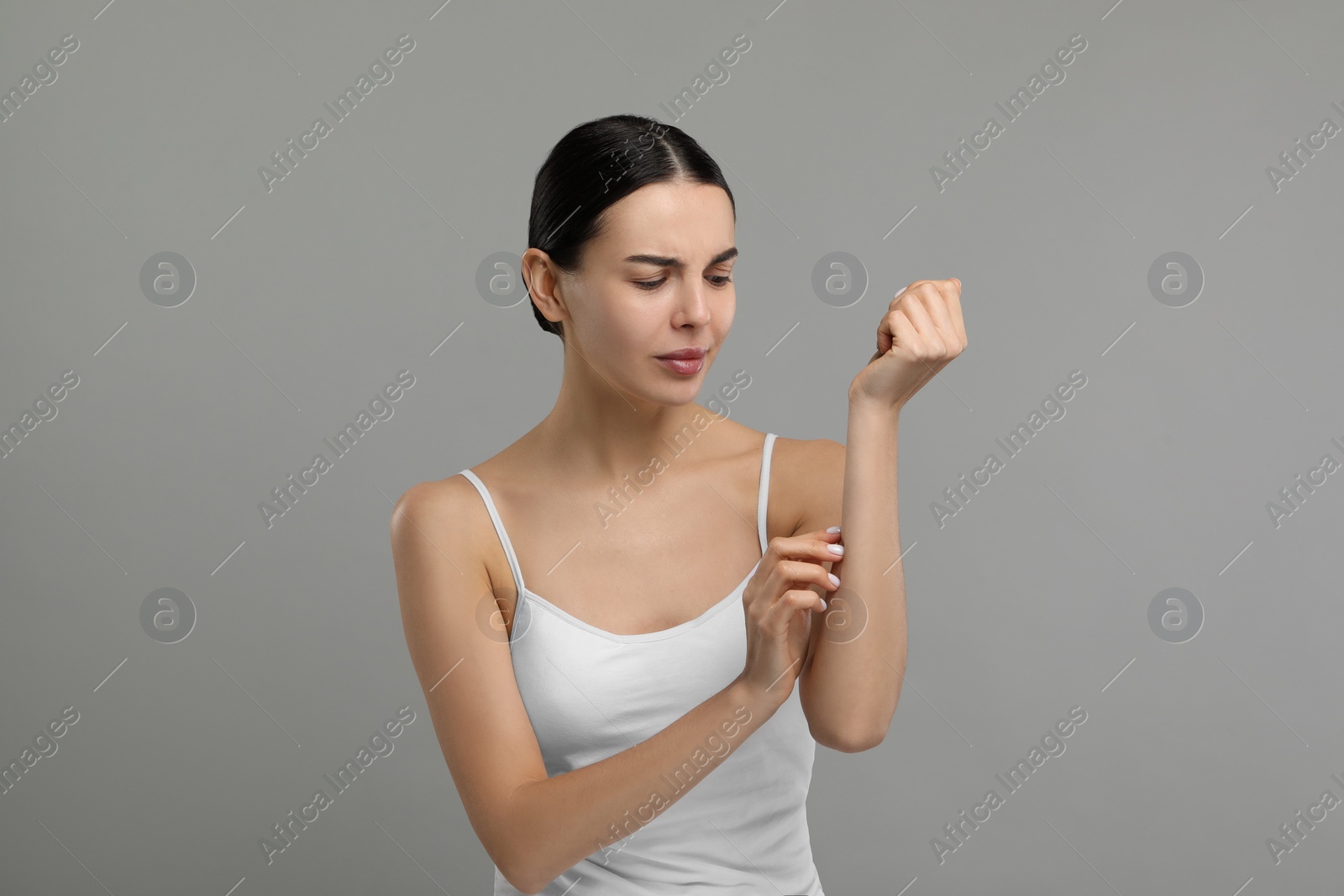 Photo of Woman with dry skin checking her arm on gray background