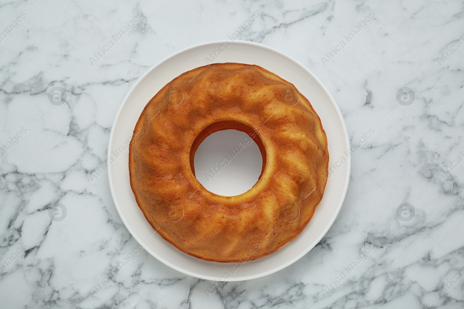 Photo of Homemade yogurt cake on white marble table, top view