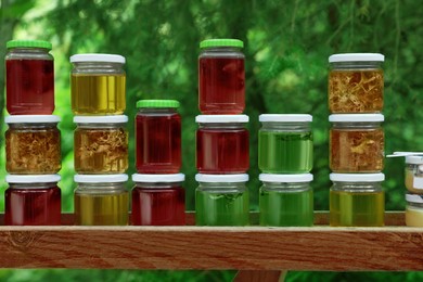 Photo of Different types of honey in jars on wooden table outdoors