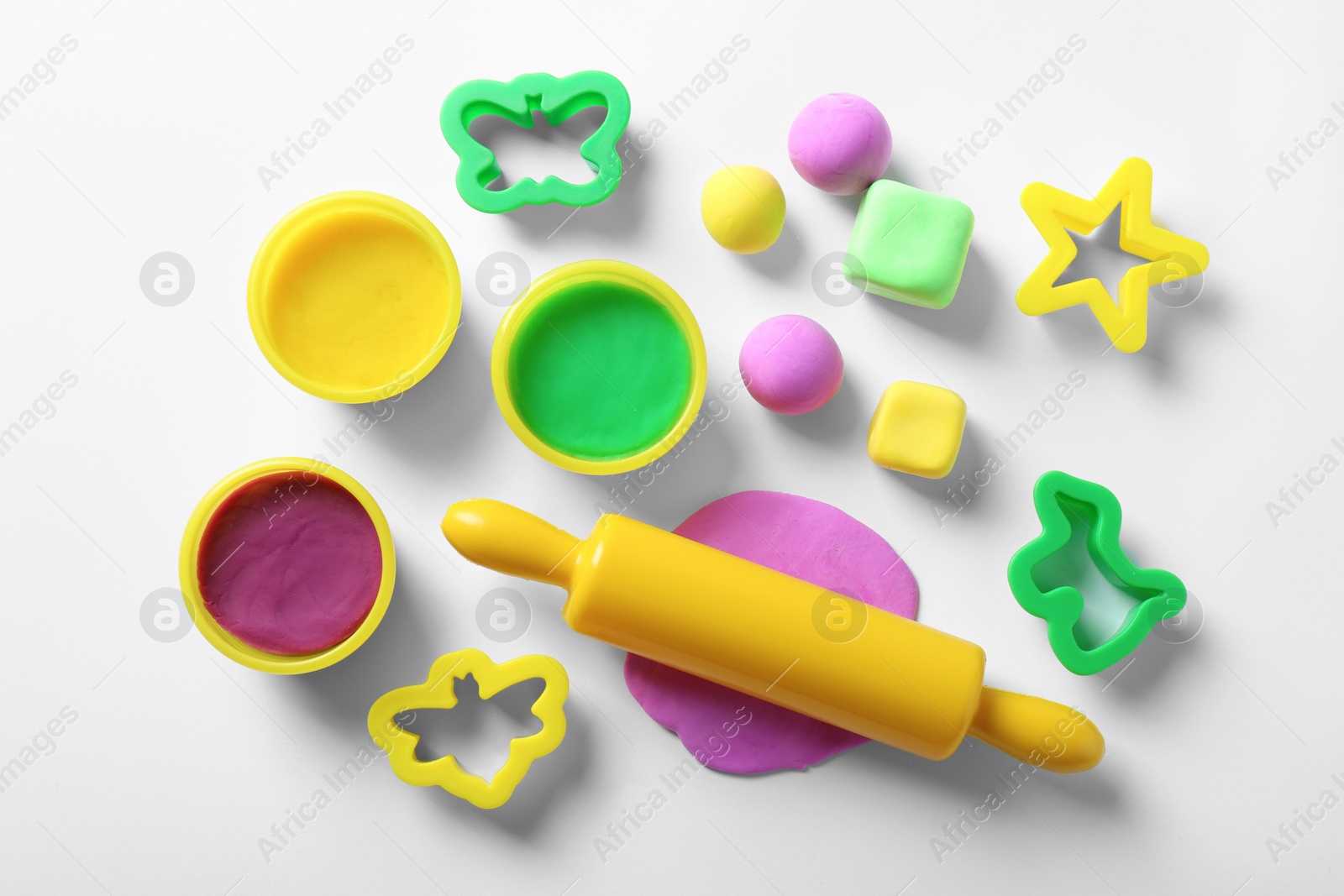 Photo of Set of tools and color play dough on white background, top view