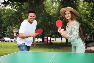 Happy couple playing ping pong in park