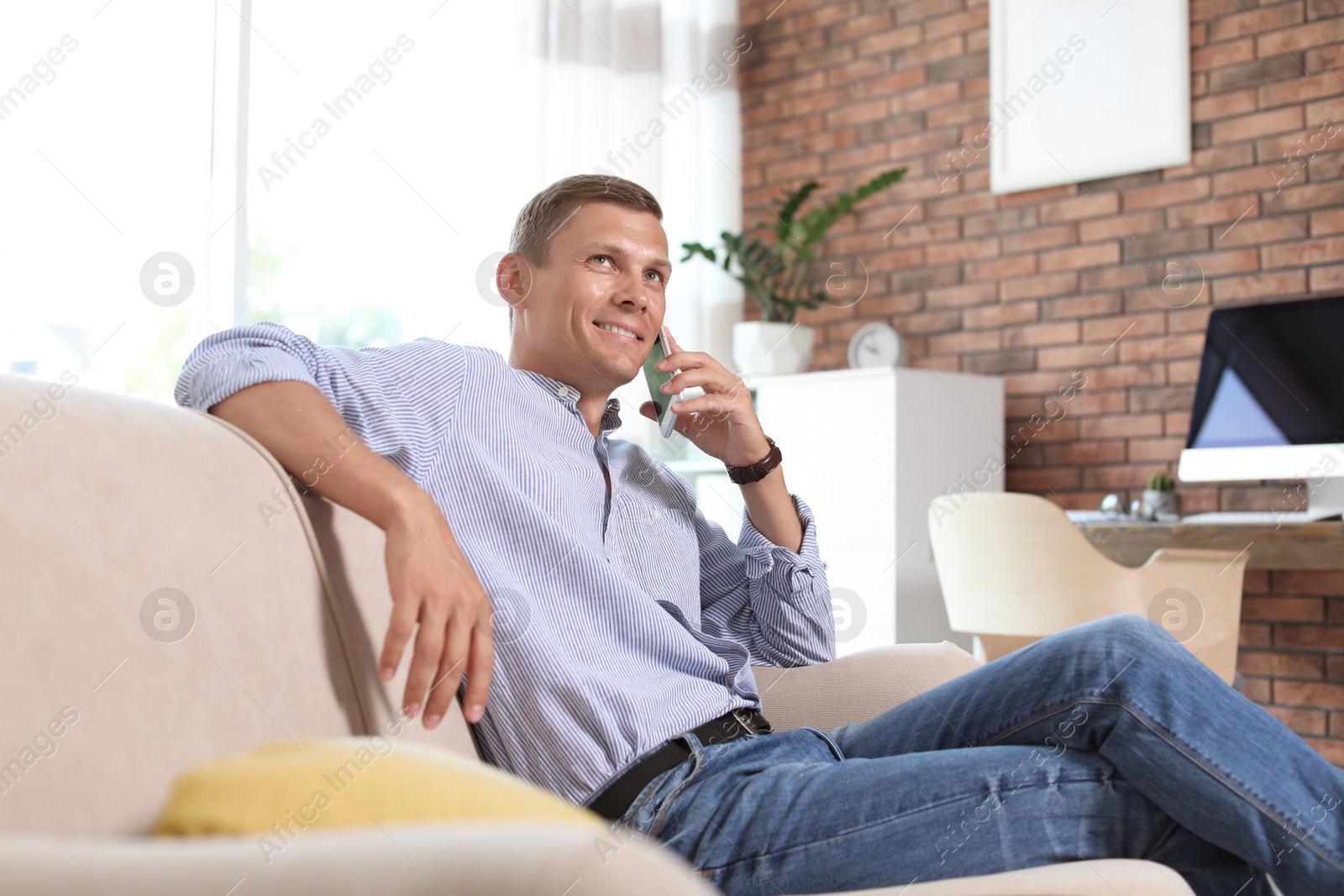 Photo of Young man talking on phone in home office. Time to work