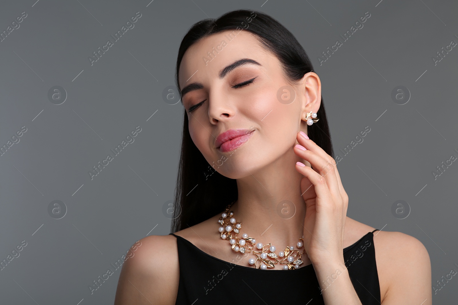 Photo of Beautiful young woman with elegant jewelry on dark grey background