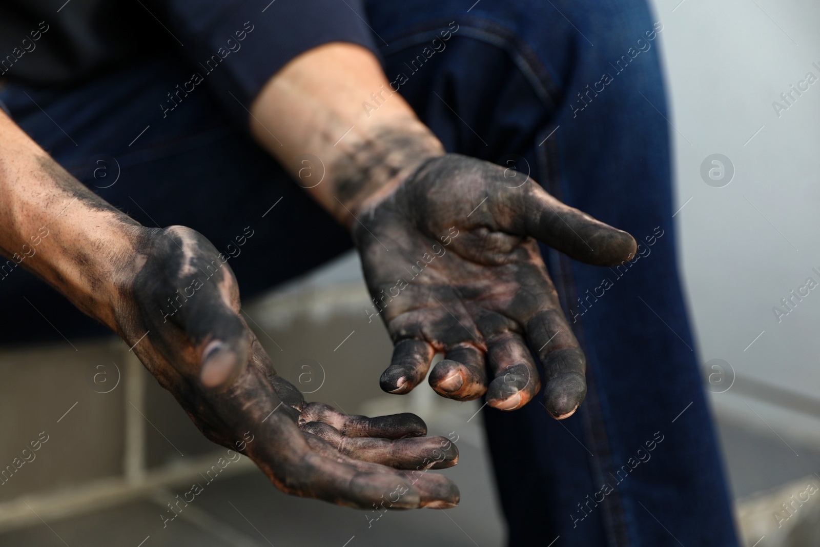 Photo of Dirty worker sitting on stairs, closeup of hands