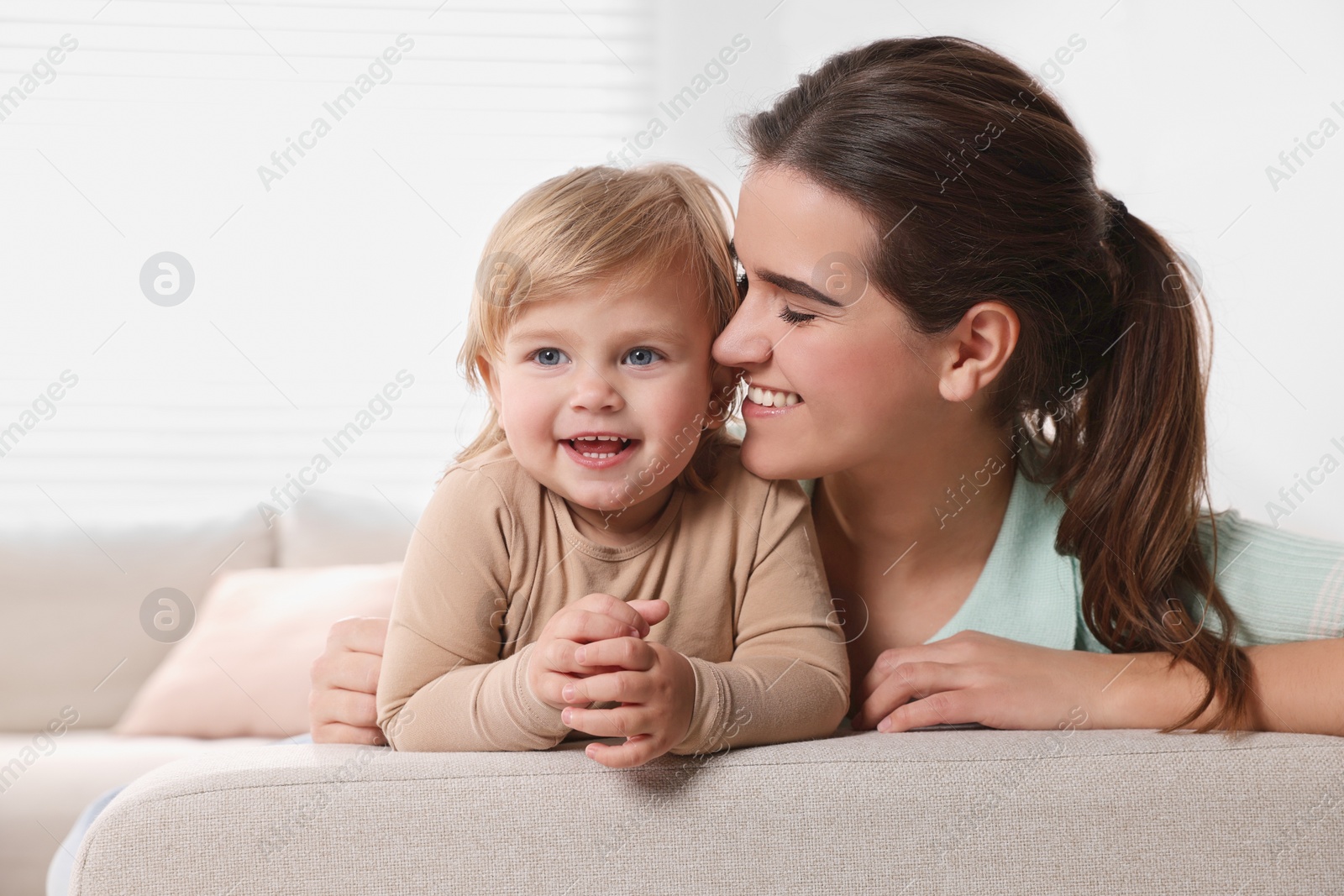 Photo of Mother with her cute little daughter on sofa at home, space for text