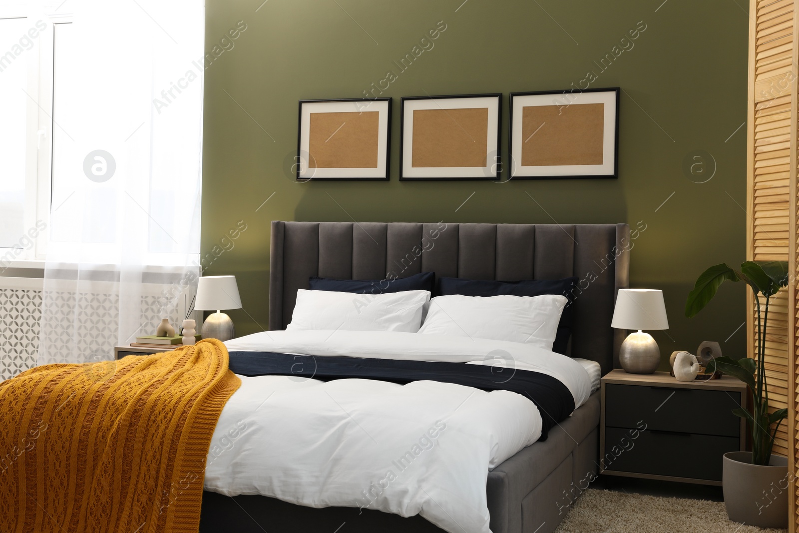 Photo of Large comfortable bed, lamps and houseplant in stylish room. Interior design