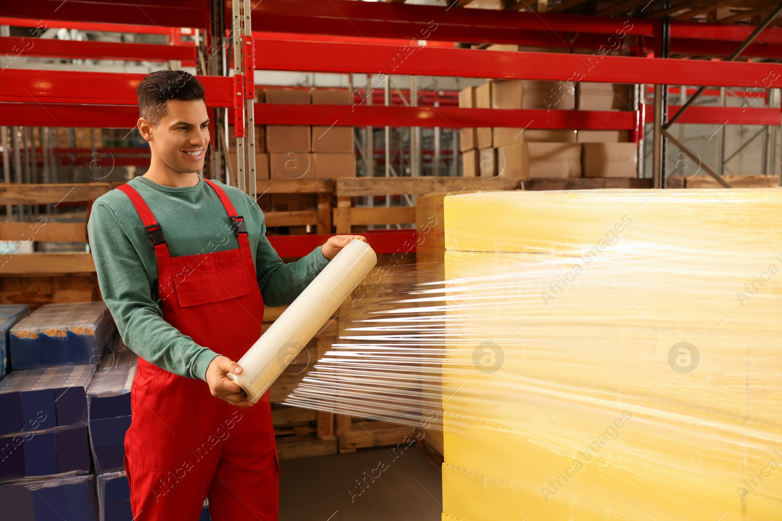 Photo of Worker wrapping boxes in stretch film at warehouse