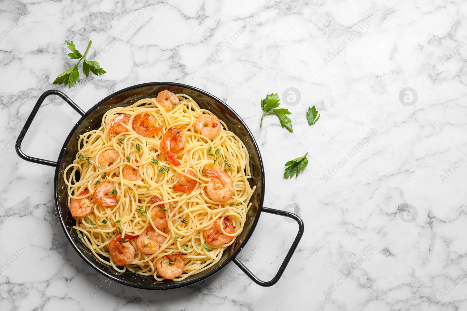 Photo of Frying pan with spaghetti and shrimps on light background, top view