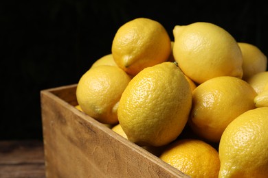 Fresh lemons in wooden crate on table, closeup