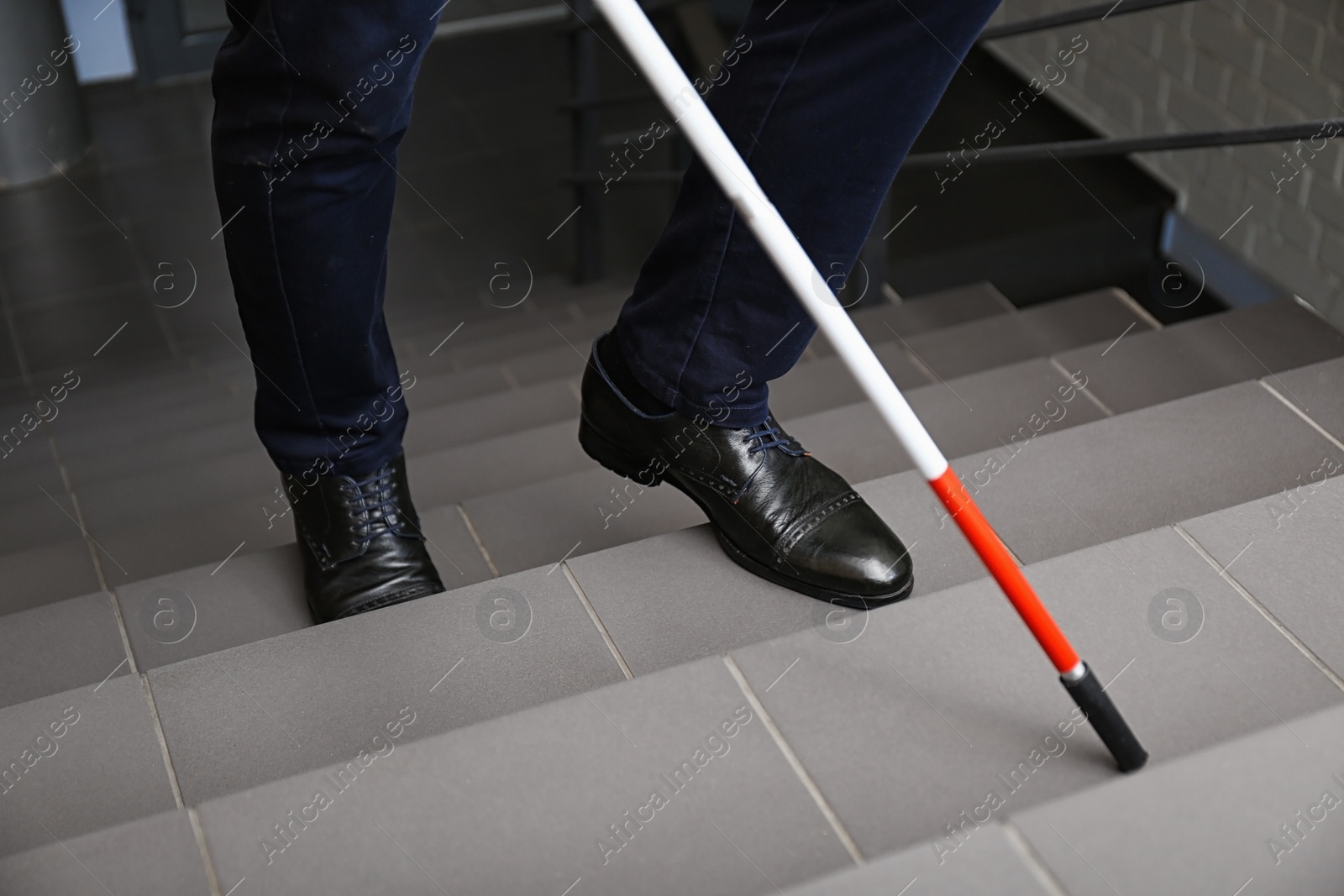 Photo of Blind person with long cane going up stairs, closeup