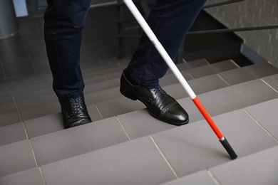 Blind person with long cane going up stairs, closeup