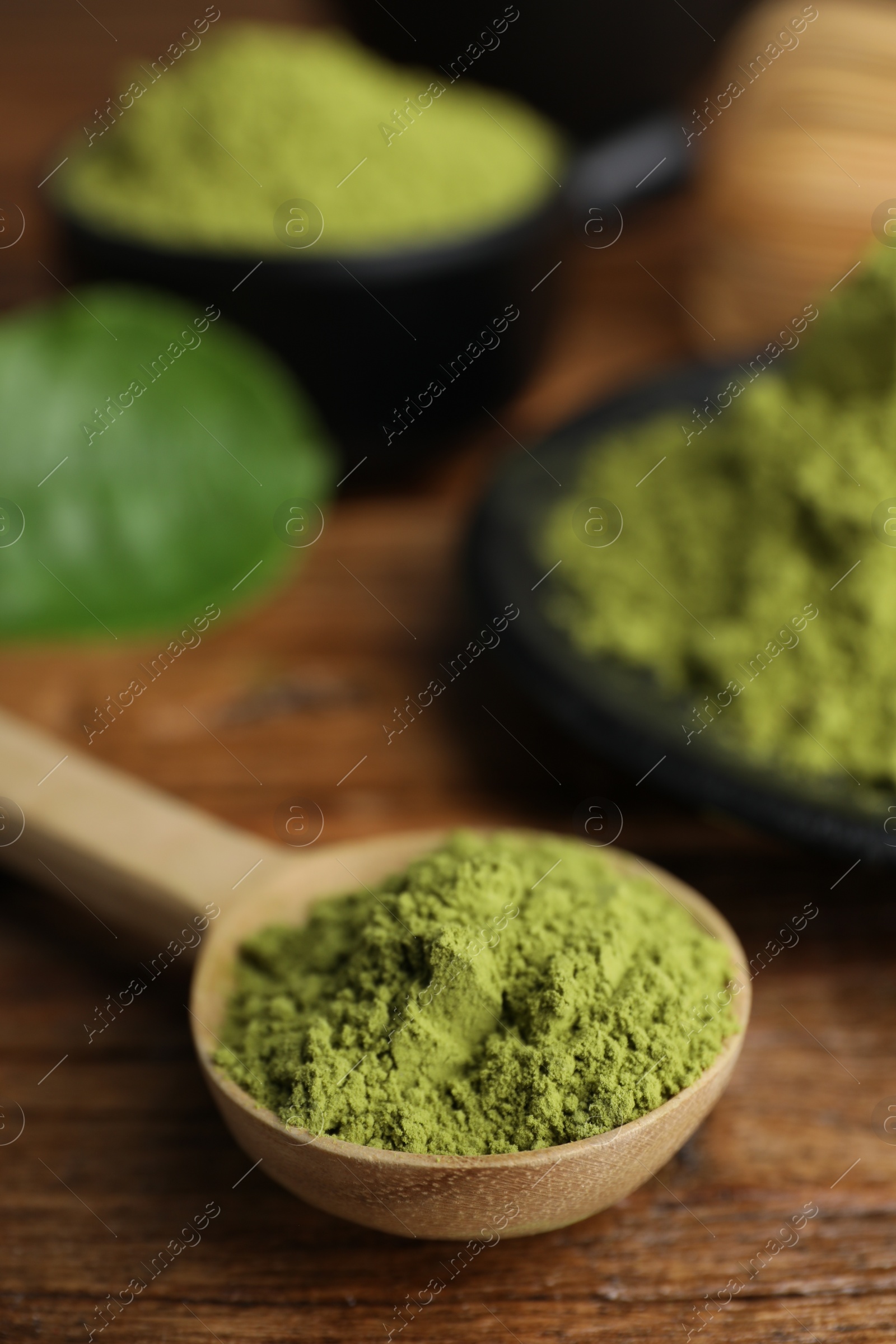 Photo of Scoop with green matcha powder on wooden table, closeup. Space for text