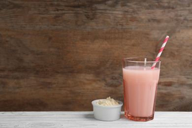 Photo of Protein shake and powder on white wooden table, space for text