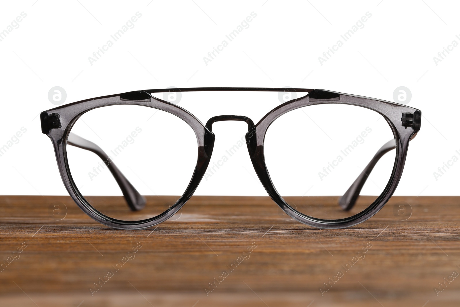 Photo of Stylish glasses with plastic frame on wooden table against white background