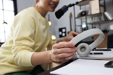 Photo of Woman working as radio host in modern studio, focus on headphones