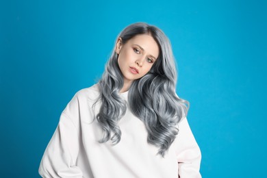Image of Portrait of beautiful woman with ash hair color on light blue background