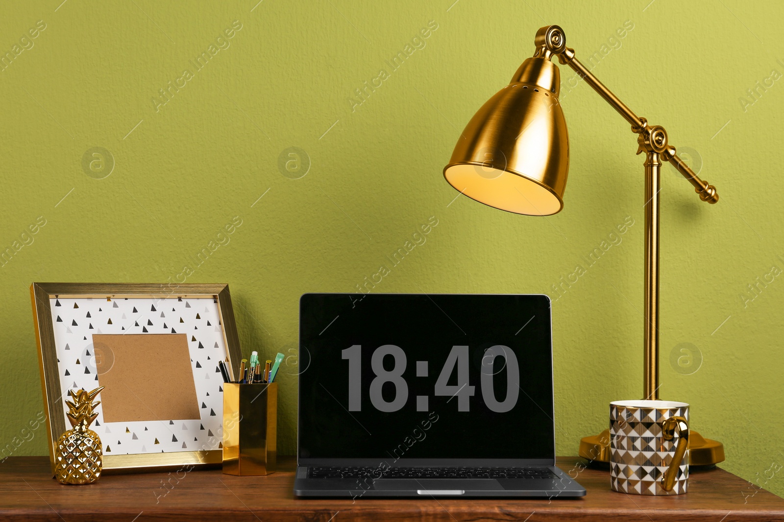 Photo of Modern workplace with laptop and golden decor on desk near wall. Stylish interior design