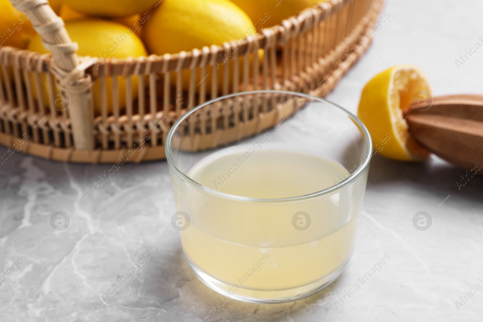 Photo of Freshly squeezed lemon juice and reamer on marble table