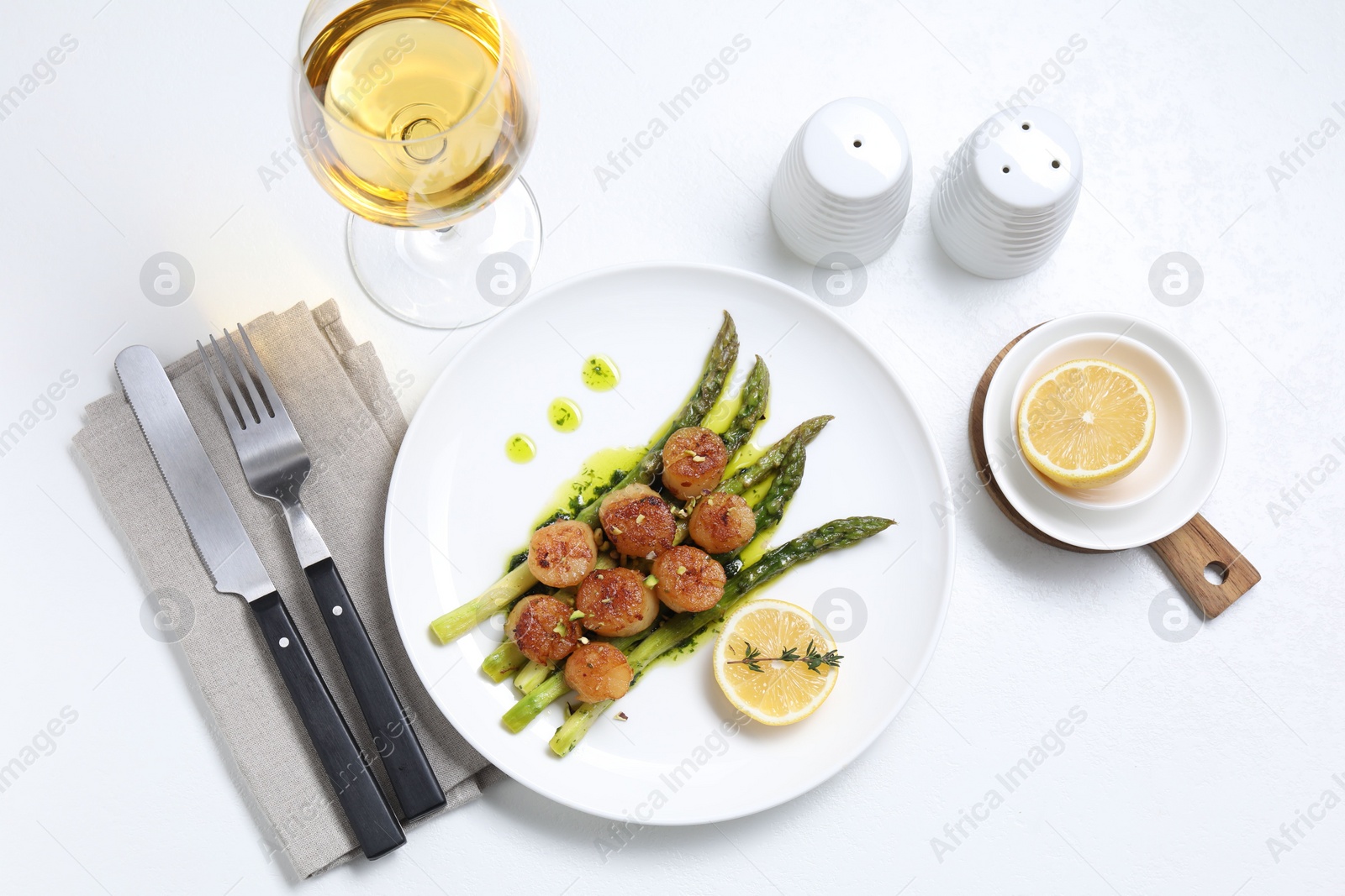 Photo of Delicious fried scallops with asparagus, lemon and thyme served on white table, flat lay