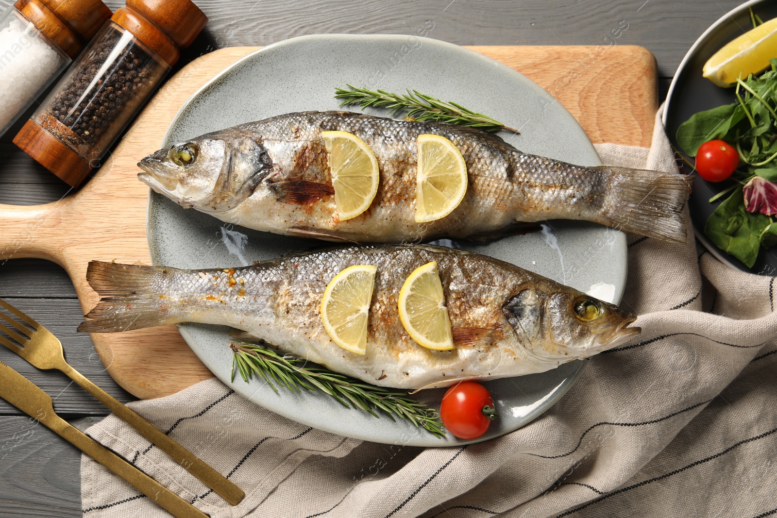 Photo of Delicious baked fish served on grey wooden table, top view