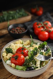 Bowl of delicious pasta with tomatoes, broccoli and cheese on wooden table