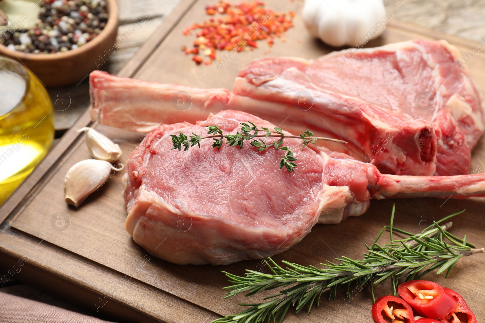 Photo of Fresh tomahawk beef cuts and spices on wooden board, closeup