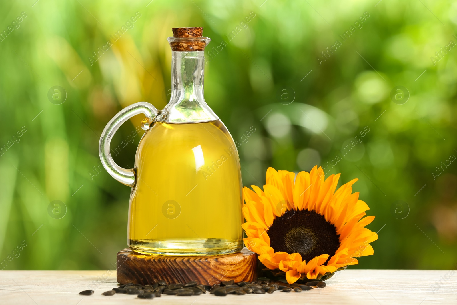 Photo of Sunflower cooking oil, seeds and yellow flower on white wooden table outdoors