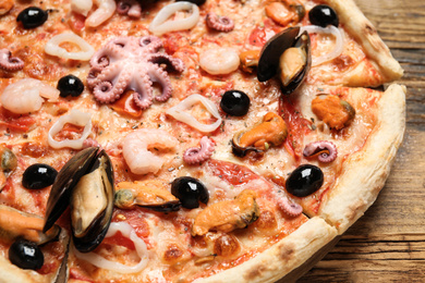 Delicious seafood pizza on wooden table, closeup
