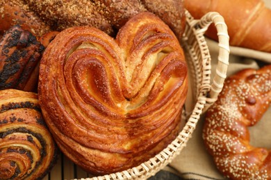 Photo of Wicker basket with different tasty freshly baked pastries on table, closeup