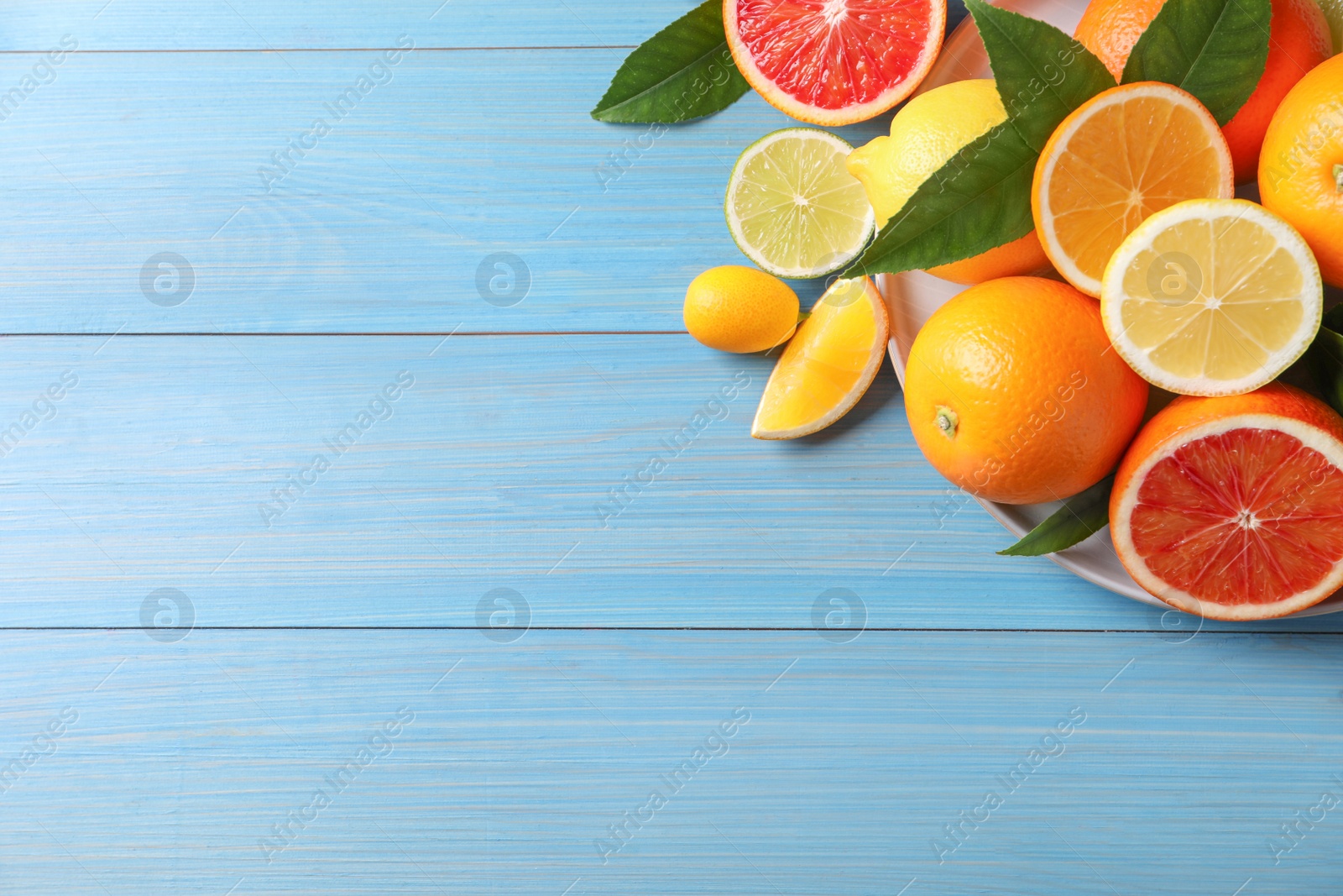 Photo of Different citrus fruits on light blue wooden table, flat lay. Space for text