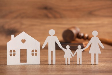 Photo of Family law. Figure of parents with children, house model and gavel on wooden table, space for text