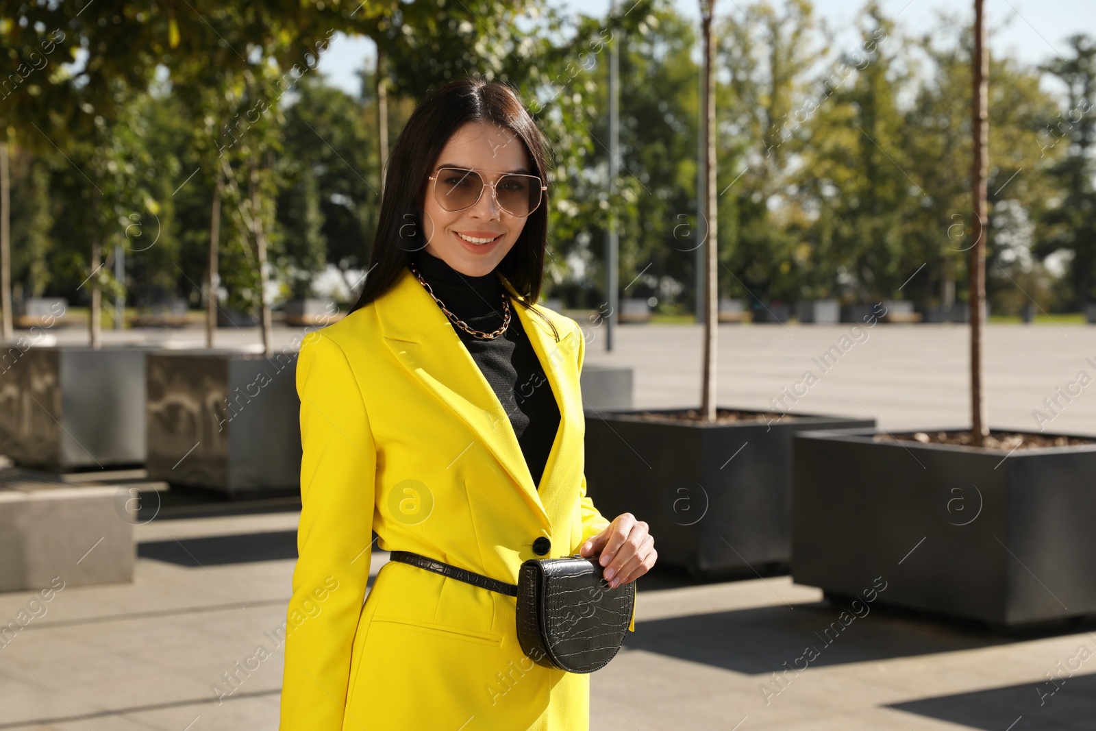 Photo of Beautiful young woman with stylish waist bag on city street
