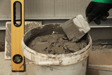 Photo of Worker taking adhesive mix with spatula, closeup