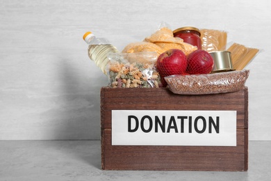 Photo of Donation box with food on table against light background