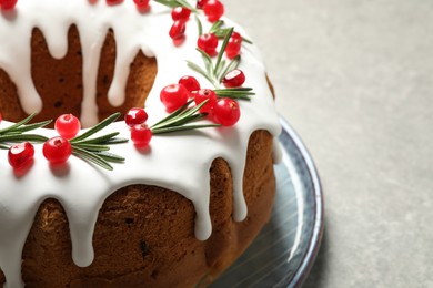 Photo of Traditional Christmas cake decorated with glaze, pomegranate seeds, cranberries and rosemary on light grey table, closeup