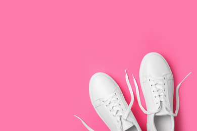 Stylish white shoes on pink background, flat lay. Space for text