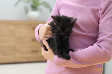Photo of Little girl with cute fluffy kitten indoors, closeup. Space for text